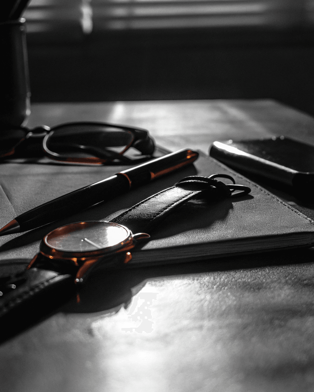 A wristwatch and pen on a leather-topped desk — finance and warranty service
