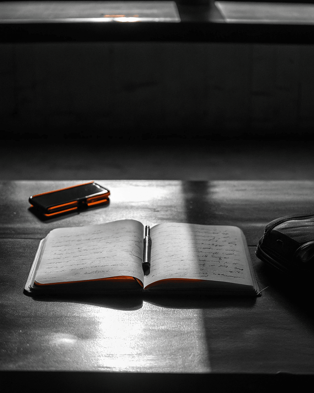 A handwritten journal, fountain pen, and smartphone on a dark wooden desk — sourcing service